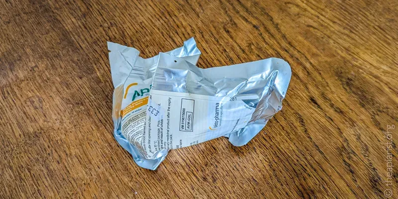 An oak tabletop with a crumpled foil sachet from Apivar